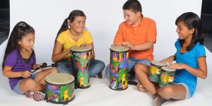 Four kids sitting on the floor and playing Remo floor drums